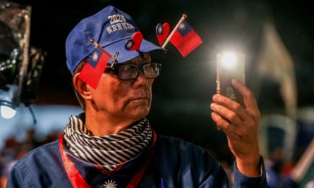 A man wears a hat adorned with Taiwan national flags and looks at his phone during an election campaign rally for the Kuomintang (Chinese Nationalist Party), in Keelung on 4 January 2024