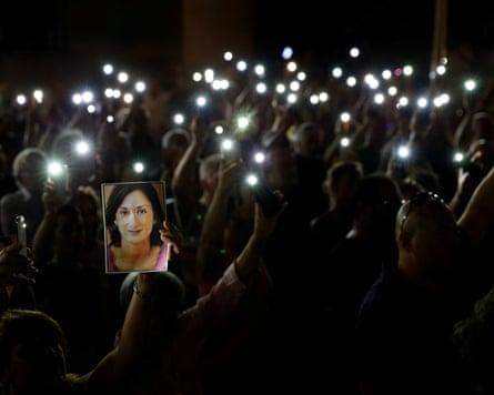 A night shot of a crowd of people holding up their mobile torches a and portrait of Daphne Caruana Galizia