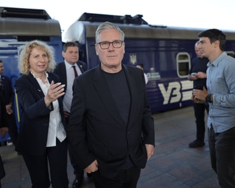 Keir Starmer walks on a train platform with other people in the background