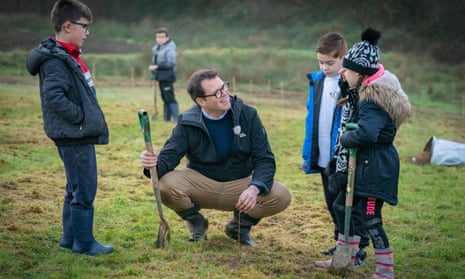 Lee Waters plants a tree with children at the Coed Cadw (Woodland Trust) woodland creation project in Neath, south Wales.