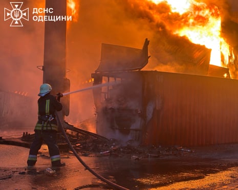 A firefighter aiming a hose at a burning building