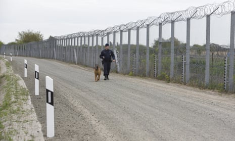 A guard with a dog walks beside Hungary's fortified border with Serbia.