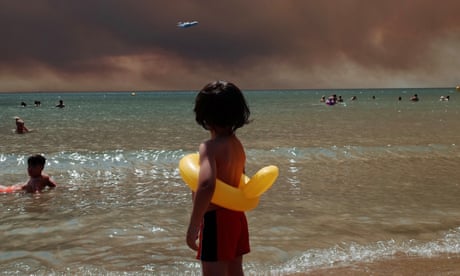 A child on a beach watches smoke from wildfires in Turkey