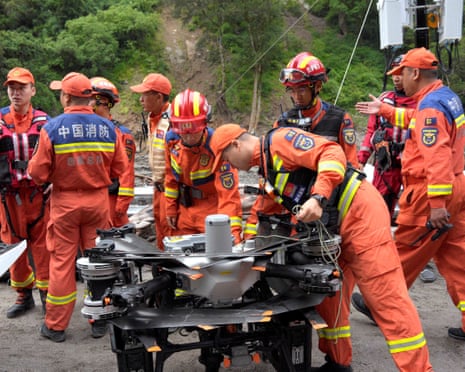 Firefighters assemble near a drone during rescue operations after the mudslide in Gyirong county in Shigatse, Tibet Autonomous Region, China