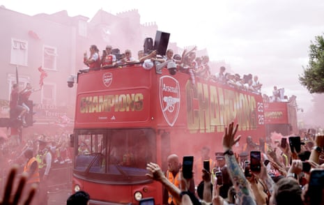 Arsenal with the Women’s Champions Cup trophy as open-topped buses drive past fans in Finsbury Park during a victory parade to celebrate Arsenal men winning the Premier League title in London