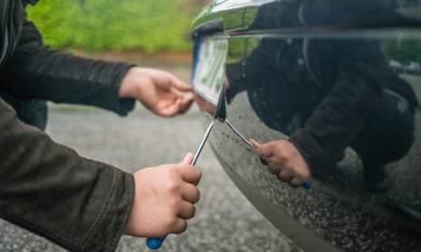 A registration plate being stolen from a car in a staged photograph