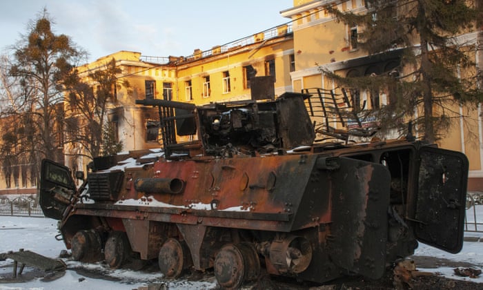 A destroyed armoured personnel carrier in front of a building damaged by shelling building in Kharkiv.