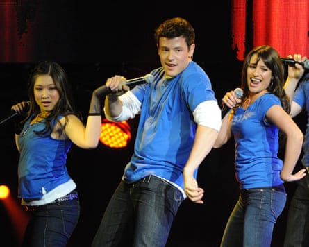 Cory Monteith with two other singers on stage in Glee.