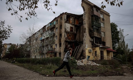 A man runs beside a destroyed apartment block in Bakhmut in Donetsk, Ukraine
