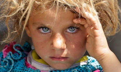 A displaced Yazidi child fleeing violence rests at the Syrian border.
