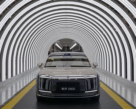 A futuristic car glides towards the camera in a tunnel of curved strip lighting