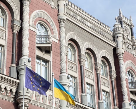 Ukrainian and EU flags flutter in front of National Bank building in Kyiv, Ukraine.