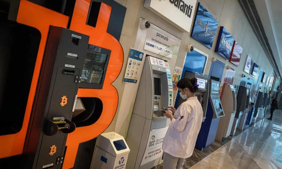 A woman uses a bank ATM next to a Bitcoin ATM machine at a shopping mall in Istanbul