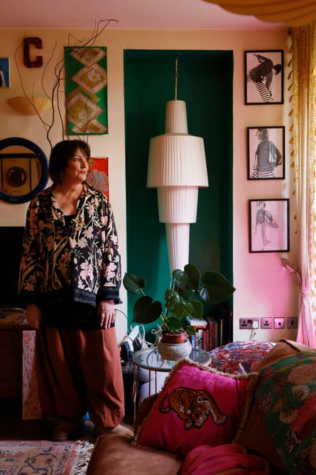 The actress Daniela Nardini stands in front of a wall of art and next to a large light feature in a green alcove.