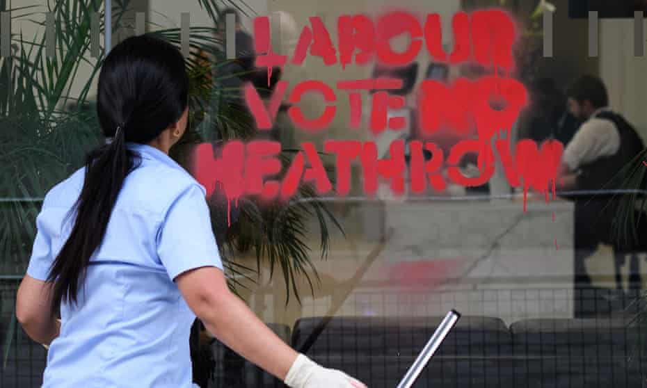 A woman cleans graffiti from the windows of the Labour Party headquarters following a protest by campaigners, calling for Labour to stop the planned expansion of Heathrow, 4 June in London