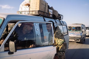 A man in uniform talks to driver at a checkpoint in Syria
