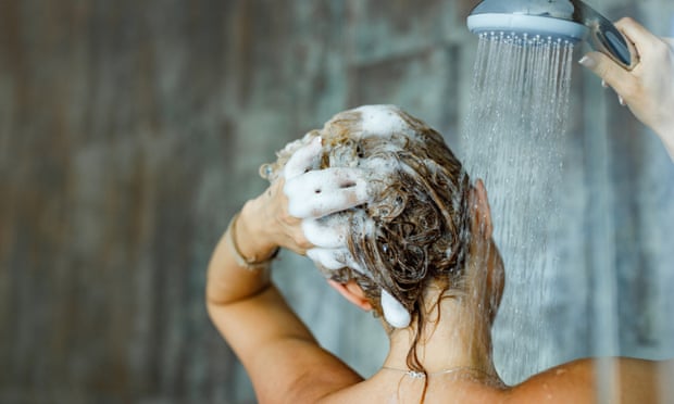 A woman washes her hair using a shower