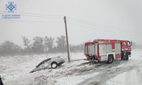 Emergency workers release a car stuck in snow during a heavy snow storm in the Odesa region, Picture released 27 November.