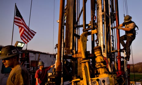 Men climbing a natural gas drill pipe with a US flag on the left of the image