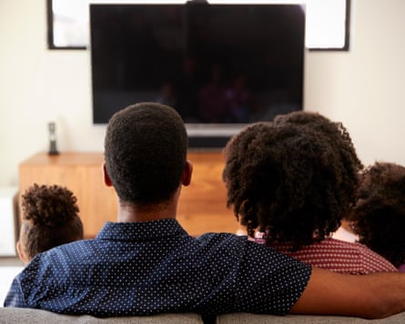 A family watch TV together.