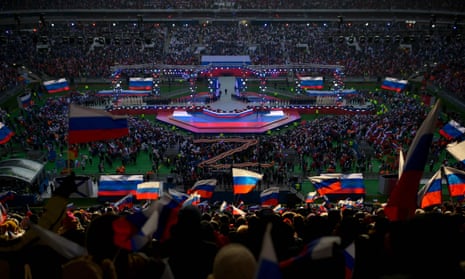 People wave Russian flags as President Vladimir Putin walks on the stage to give a speech during a patriotic concert dedicated to the upcoming Defender of the Fatherland Day at the Luzhniki stadium in Moscow on February 22, 2023.