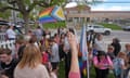 Parents and kids gather in front of a school with a trans rights flag.