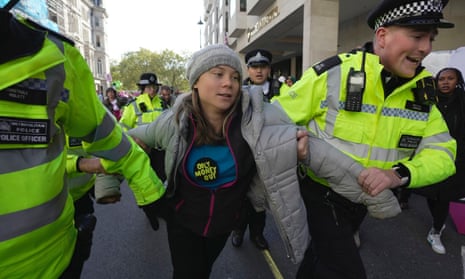 Greta Thunberg between two Met police officers