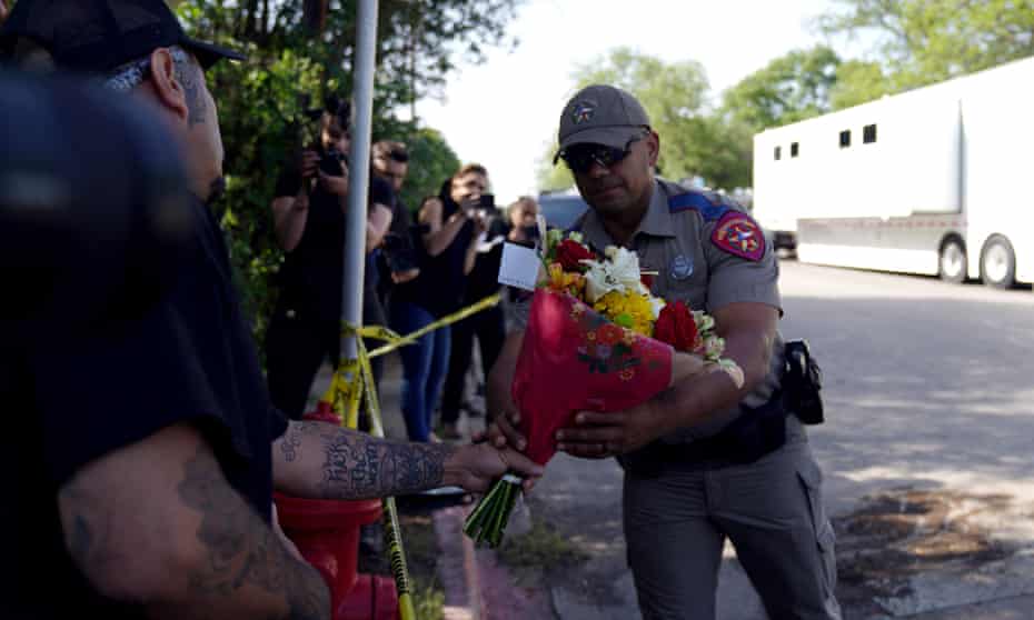 A police officer takes flowers from a resident to be placed at a makeshift memorial outside Robb elementary school in Uvalde, Texas.