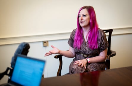 Alice Outten, who has long pink hair, speaks into a microphone while accepting medal.