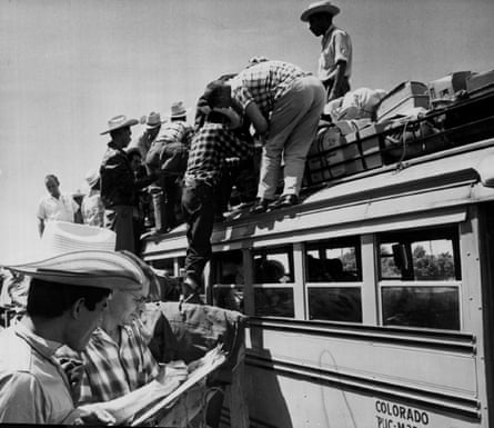a man checks a name on a sheet as others load their belongings on a bus