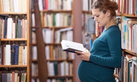a pregnant woman reading in a library.