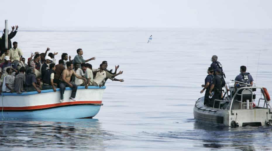 Armed Forces of Malta marines toss bottles of water to a group of around 180 illegal immigrants as a rescue operation gets underway.