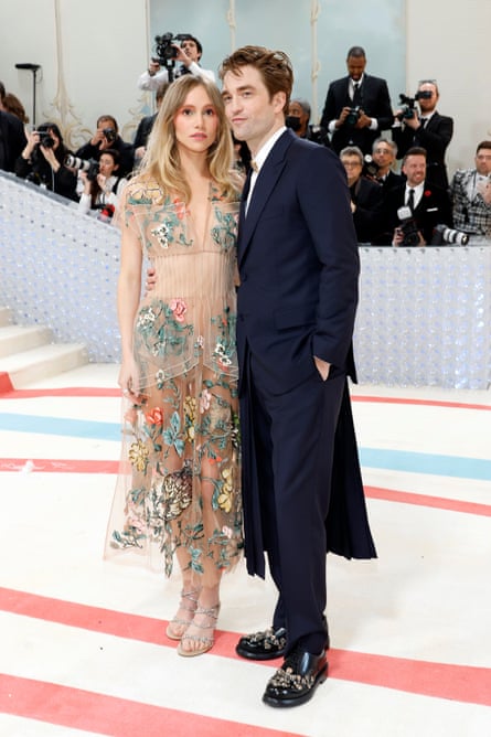 Pattinson poses in a dark blue suit and Waterhouse in a sheer, floral-embroidered Fendi dress at the 2023 Met Gala