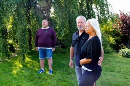 the three stand on a green lawn in a garden; Harry’s mother stands with his stepfather in the foreground while his father is behind them under a willow tree.