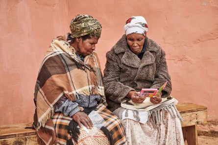 Mateboho Molutsi (left) and Jocelyn Femele (right) are part of a group that has gathered to learn about HIV treatment in the village of Ramafolo. They took the talking book outside to listen to it together.