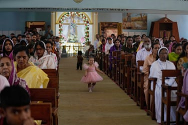 A girl runs through a church service in Jammu, wearing a pink dress
