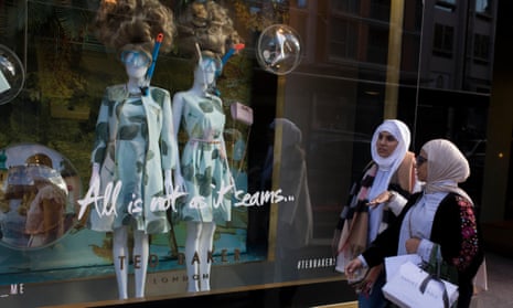 Two women walk past a display of mannequins in diving masks and snorkels, outside a central London branch of Ted Baker.