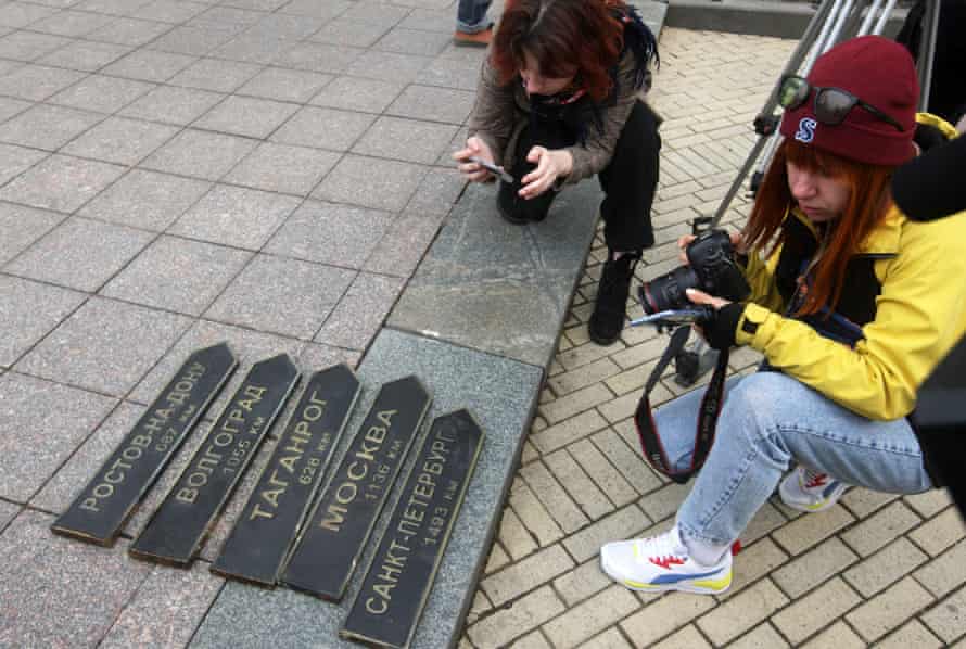 Journalists take photos of dismantled Russian twin city signs from a memorial in the centre of Odesa, Ukraine.