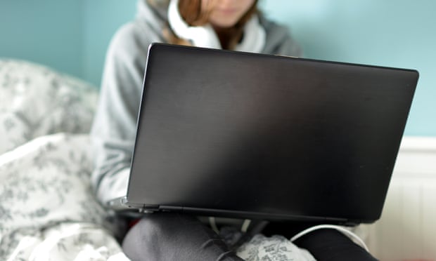 A teen girl on a laptop in her bedroom