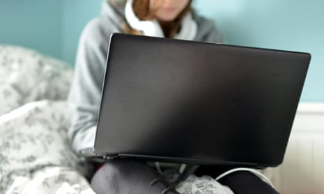 A teenage  girl on a laptop in her bedroom