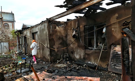 A person walks past burnt-out buildings