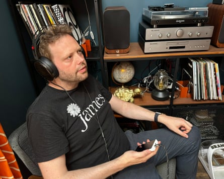 A man listens to music on an MP3 player in his house.