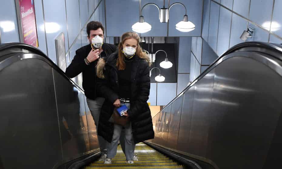 A couple wearing face masks travel on the Underground in London on 24 March.