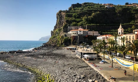 A lush green hill overlooks a rocky beach on Madeira