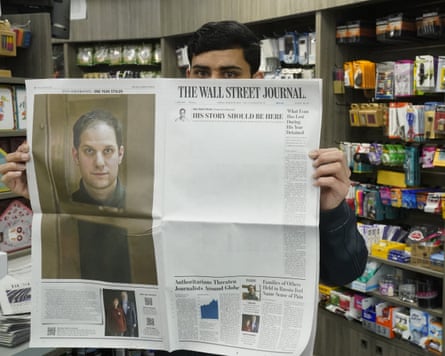 A New York City vendor holds up a copy of the Wall Street Journal with a mostly blank front page and an image of reporter Evan Gershkovich.