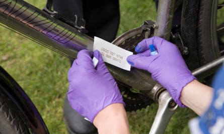 A police community support officer security marks a bicycle frame with a permanent reference number.