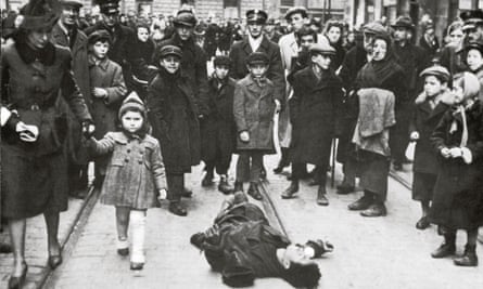 A crowd surround a dead man on the street in the Warsaw ghetto around 1940.