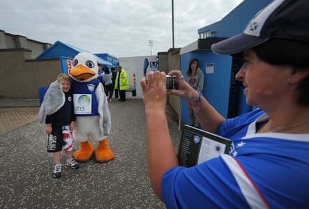 A young Rangers fan poses for a photograph with the Peterhead mascot Sammy the Scurry before the Scottish Third Division match at Balmoor Stadium in August 2012