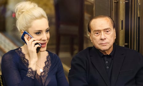 Silvio Berlusconi sits to the right of Marta Fascina while she talks on a phone
