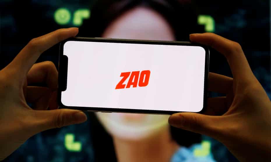 A person holds a phone showing the Zao app's logo